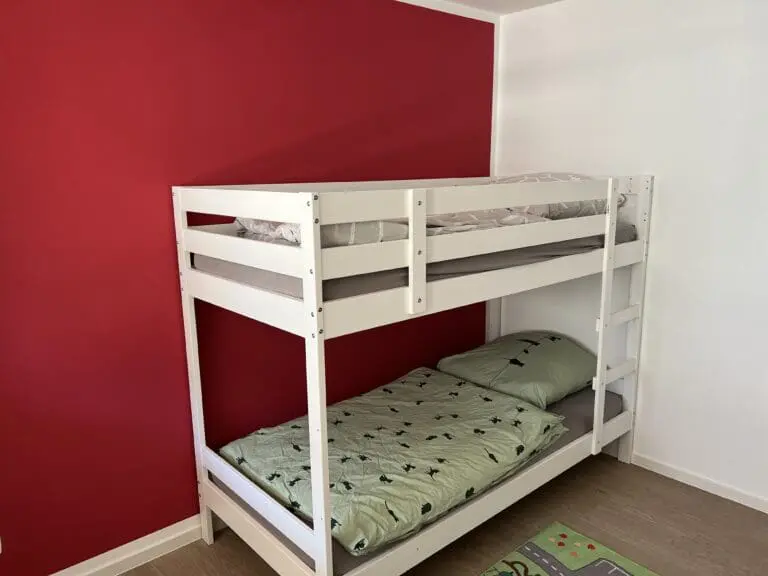 Kinderzimmer mit weißem Etagenbett vor roter Wand
