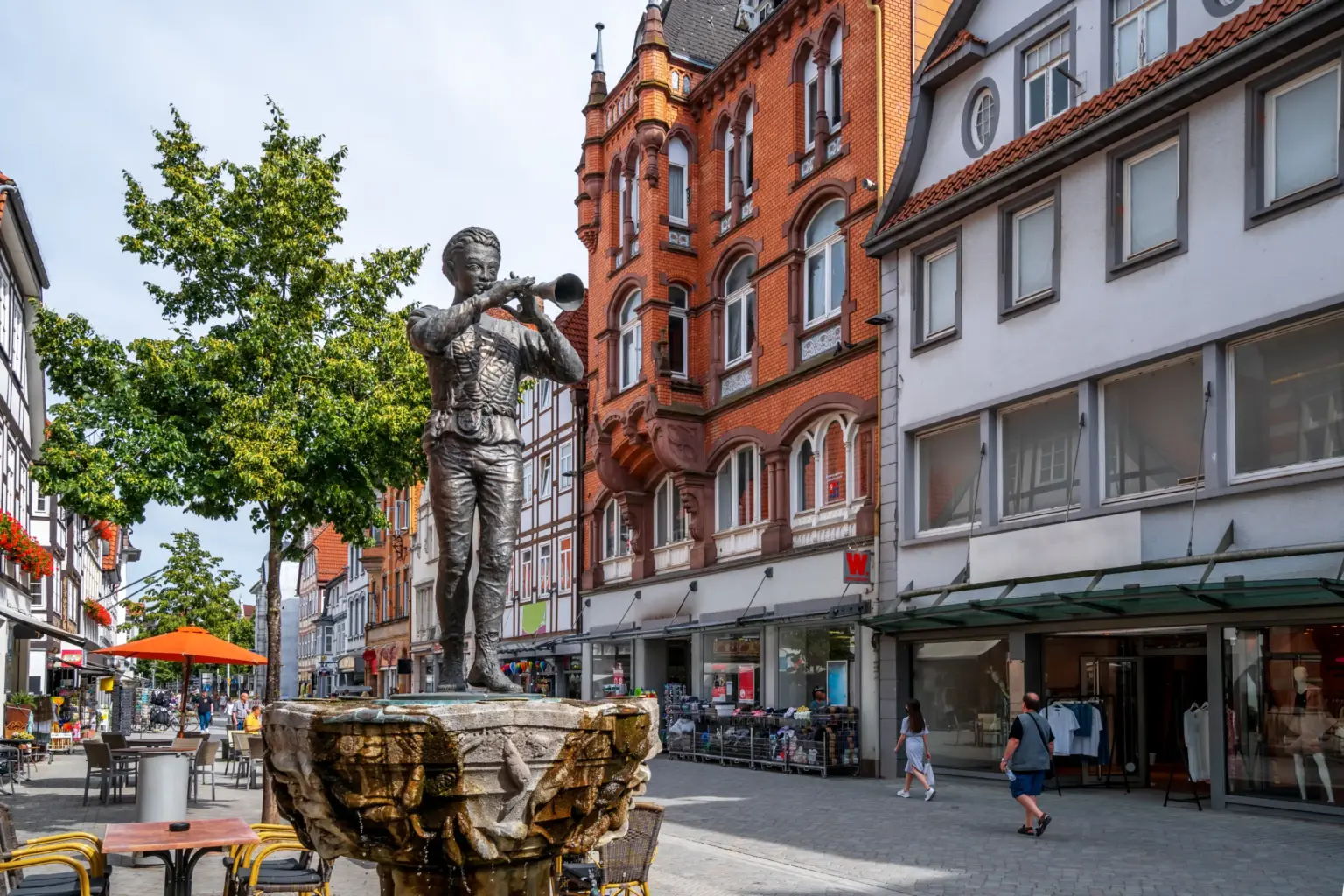 Bronzefigur des Rattenfängers mit Flöte auf einem Brunnen in der Fußgängerzone der Hamelner Altstadt