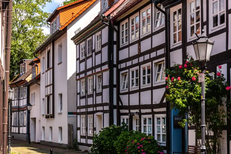 Schmale Gasse mit Fachwerkhäusern, Laterne und Rosen in der Hamelner Altstadt