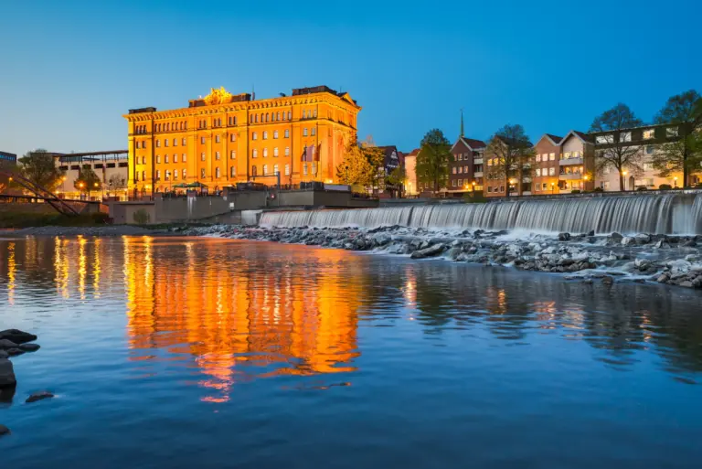 Pfortmühle an der Weser mit Wehr, abends beleuchtet und im Wasser gespiegelt